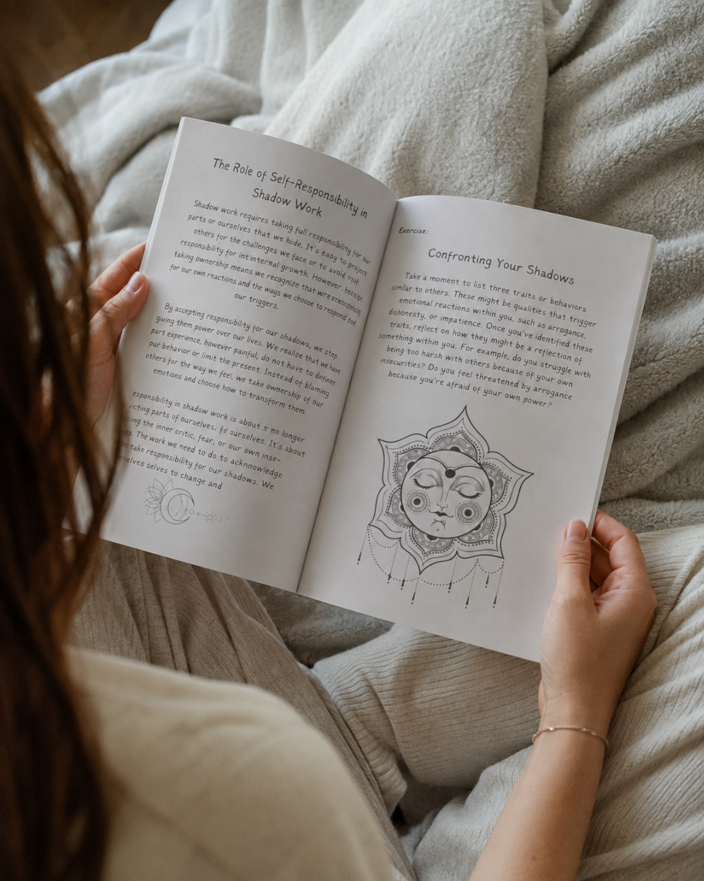 A person holding Awakened and Unstoppable personal growth workbook by Wilmaris Santos, with printed text and a sun-and-moon illustration, photographed from above while sitting on a soft beige blanket.